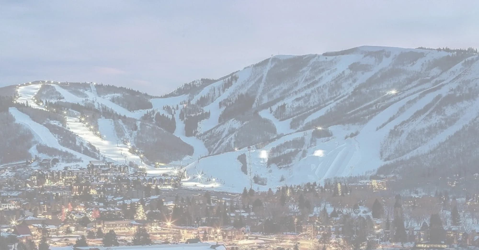 Park City ski slopes lit at dusk above the town lights